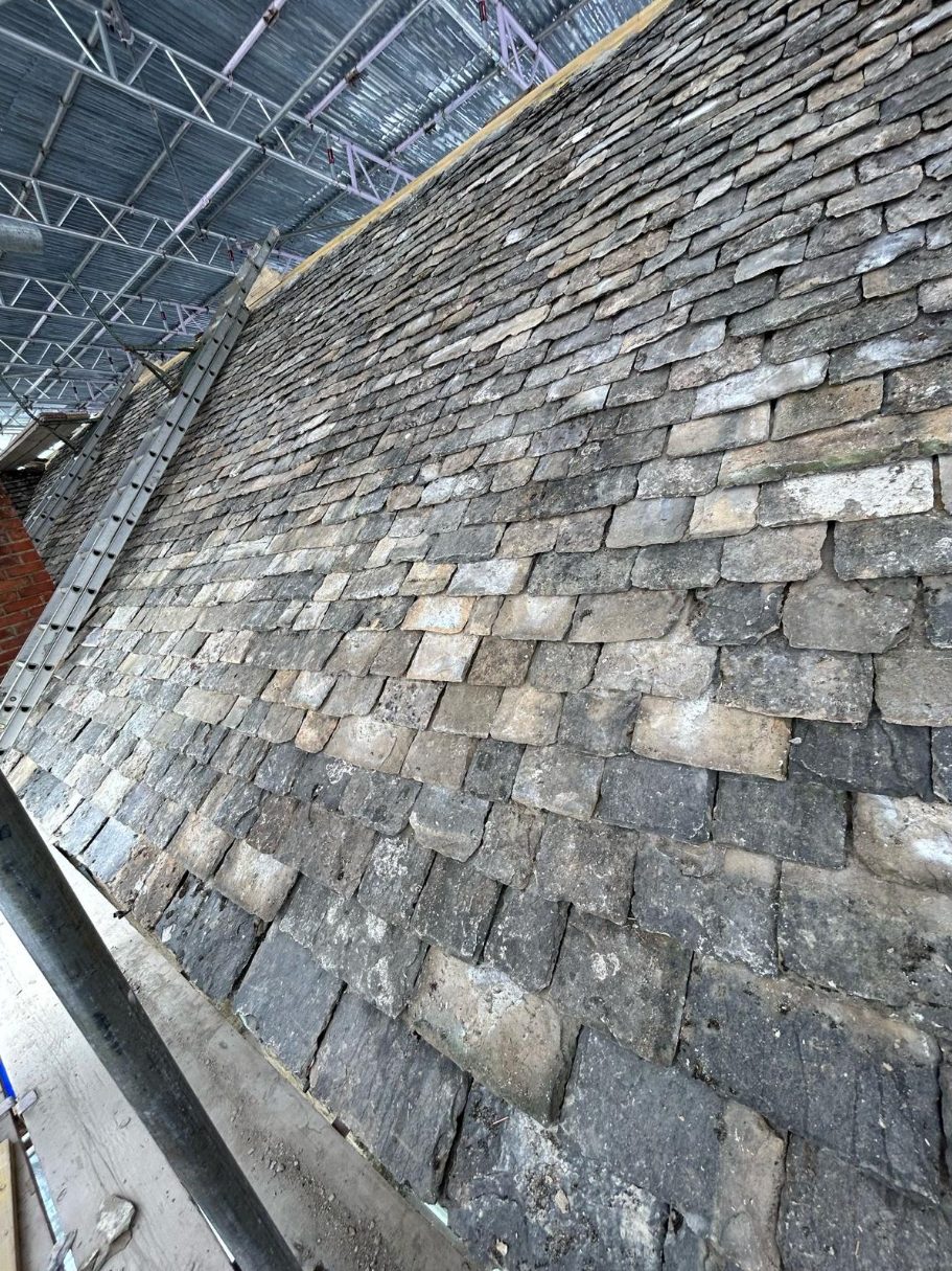 Natural stone slate roof under scaffold during restoration.