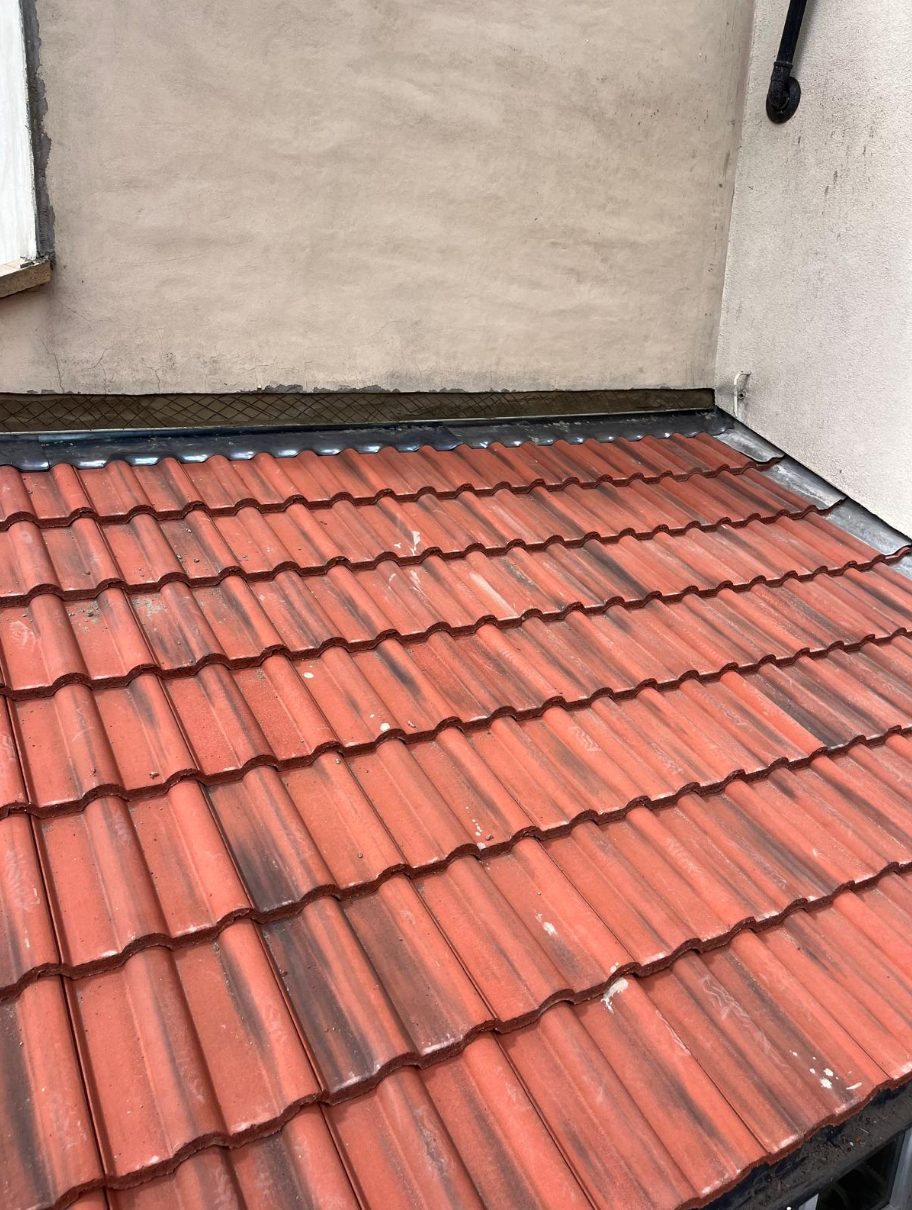 Freshly tiled lean-to roof with new lead abutment flashing.